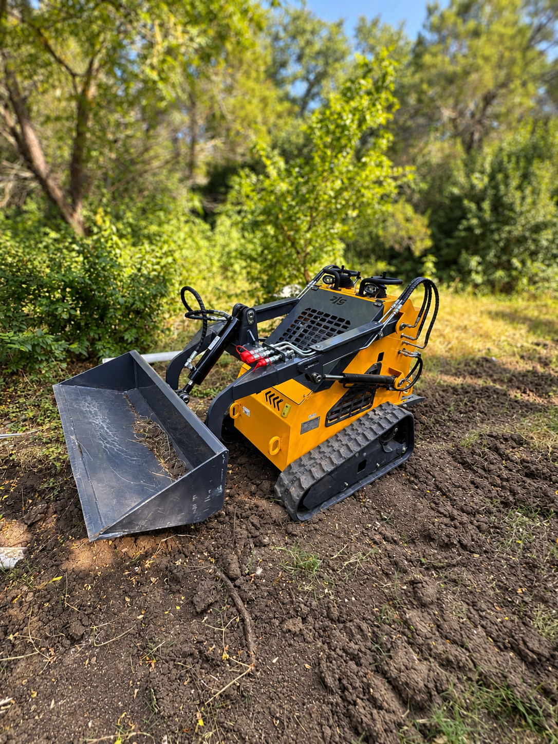 ZJ-380 mini skid steer working in a wooded area